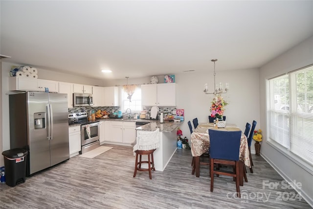 kitchen with white cabinets, kitchen peninsula, sink, and stainless steel appliances