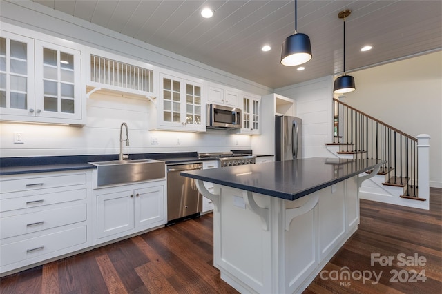 kitchen featuring white cabinetry, stainless steel appliances, dark hardwood / wood-style flooring, sink, and a breakfast bar