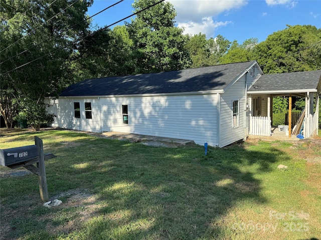 single story home with a shingled roof, covered porch, and a front lawn