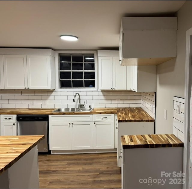 kitchen featuring dishwasher, butcher block counters, a sink, and decorative backsplash