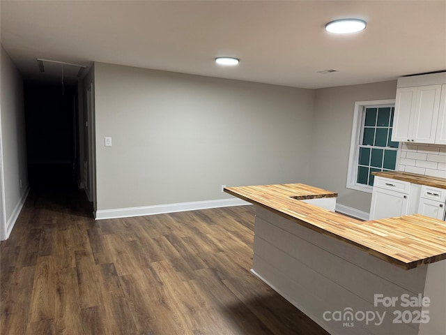 kitchen with dark wood finished floors, tasteful backsplash, wooden counters, white cabinets, and baseboards