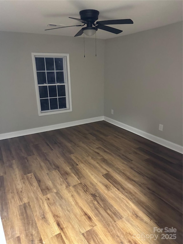 empty room with a ceiling fan, dark wood-style flooring, and baseboards