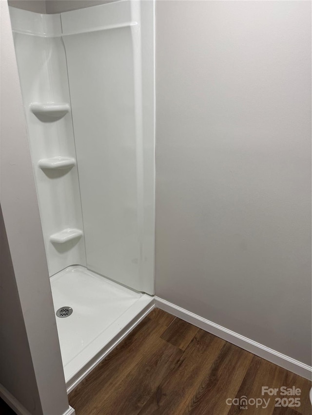 bathroom with baseboards, a shower, and wood finished floors