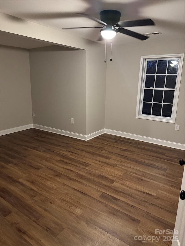 unfurnished room with baseboards, ceiling fan, visible vents, and dark wood-style flooring