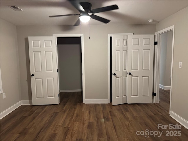 unfurnished bedroom with dark wood-type flooring, a ceiling fan, visible vents, and baseboards