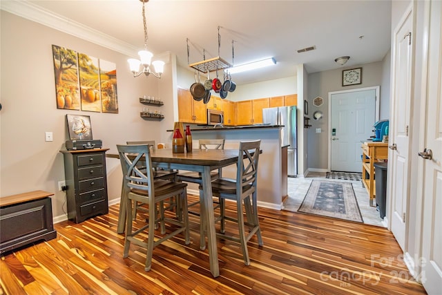 dining room featuring wood-type flooring, an inviting chandelier, and ornamental molding