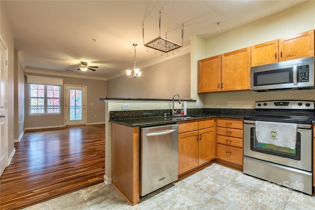 kitchen with dark stone countertops, pendant lighting, appliances with stainless steel finishes, ornamental molding, and ceiling fan with notable chandelier