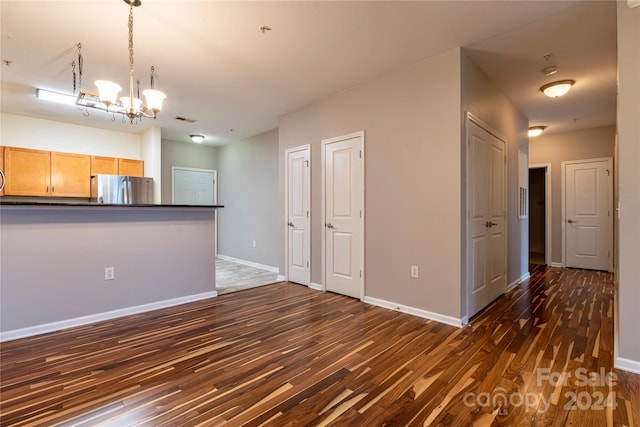 unfurnished living room featuring dark hardwood / wood-style flooring and a chandelier