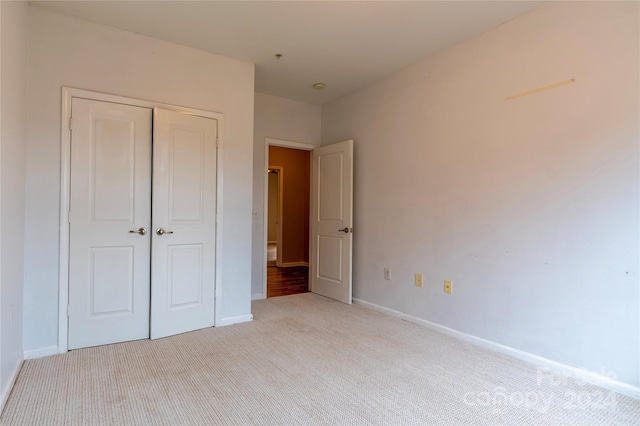 unfurnished bedroom featuring light carpet and a closet