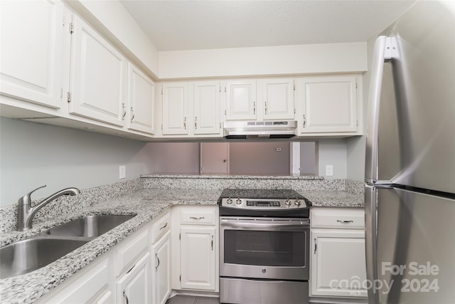 kitchen with stainless steel appliances, sink, light stone countertops, and white cabinets