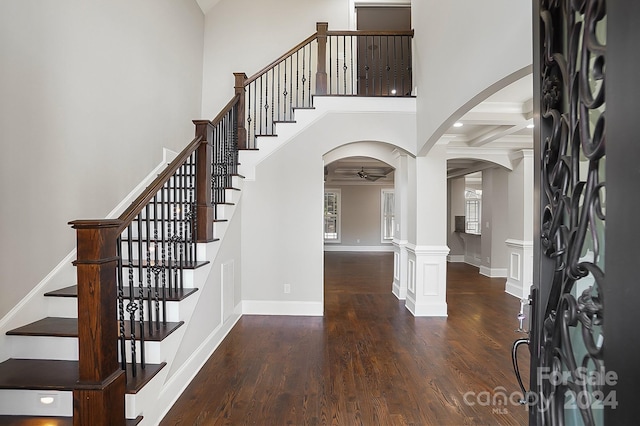 entrance foyer featuring dark hardwood / wood-style flooring, beam ceiling, ornate columns, and coffered ceiling