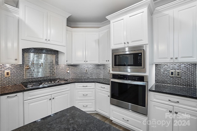 kitchen with tasteful backsplash, dark stone countertops, stainless steel appliances, and white cabinetry