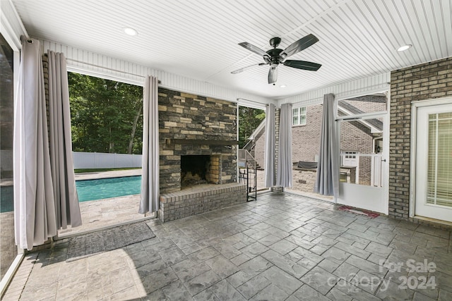 unfurnished living room featuring ceiling fan and an outdoor fireplace