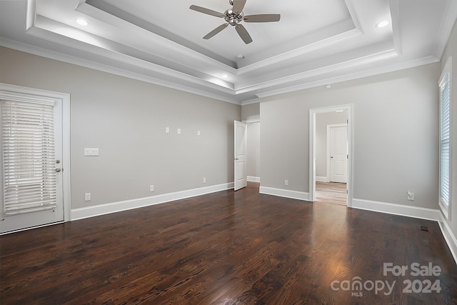 empty room featuring ceiling fan, dark wood-type flooring, crown molding, and a tray ceiling