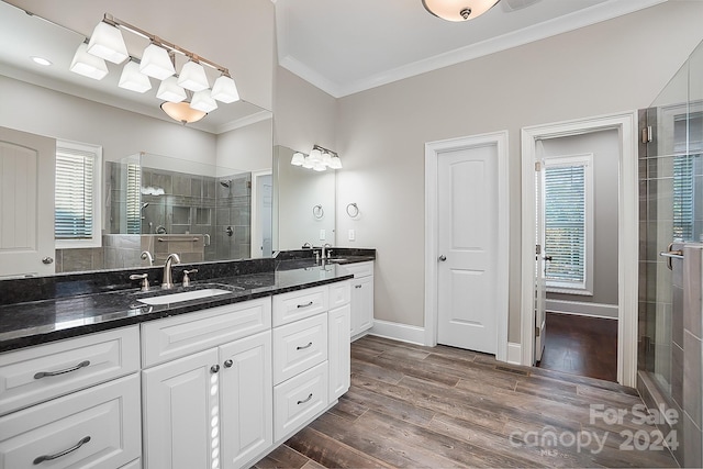 bathroom with hardwood / wood-style floors, walk in shower, crown molding, and vanity