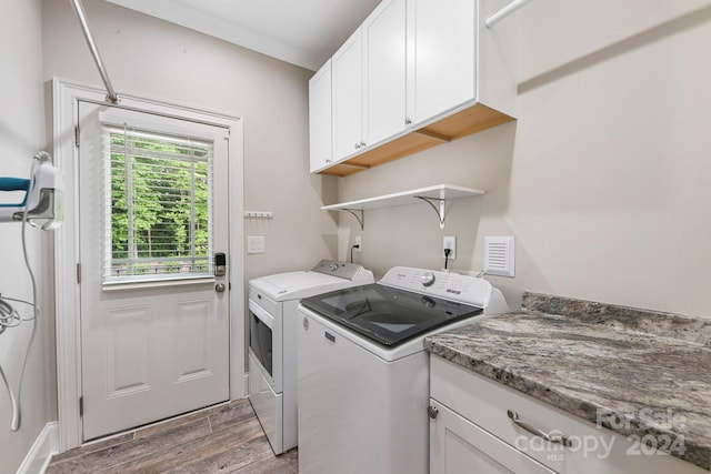 laundry room featuring cabinets, washing machine and clothes dryer, and light hardwood / wood-style flooring