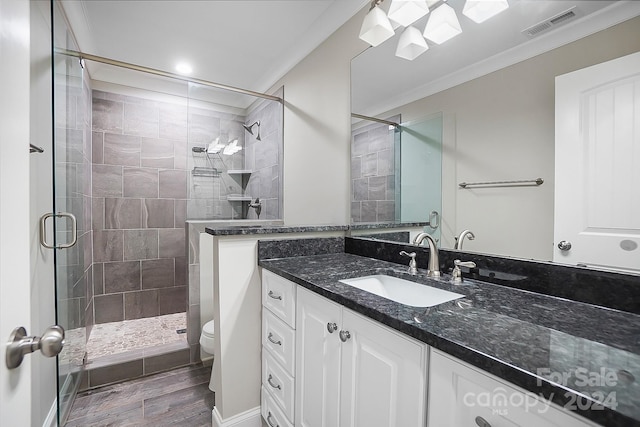 bathroom featuring a shower with shower door, vanity, toilet, hardwood / wood-style flooring, and crown molding