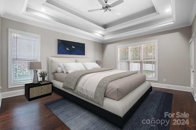 bedroom with ceiling fan, a tray ceiling, dark hardwood / wood-style floors, and crown molding