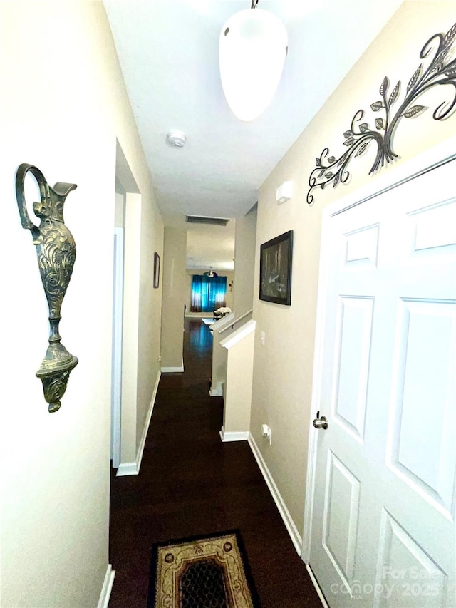 hallway with visible vents, baseboards, and wood finished floors