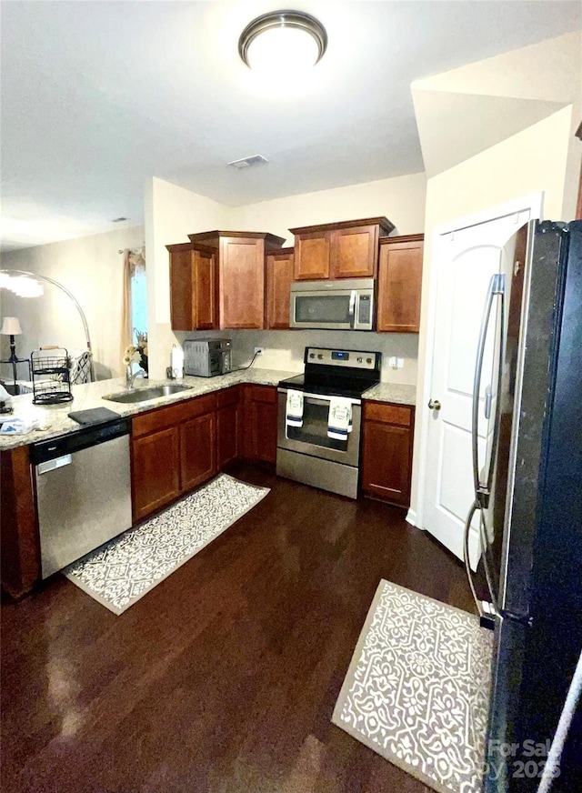 kitchen with visible vents, appliances with stainless steel finishes, brown cabinets, light countertops, and a sink