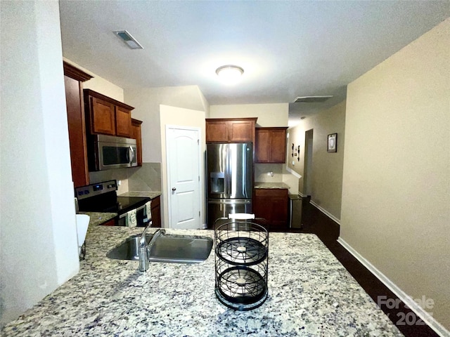 kitchen with baseboards, visible vents, light stone counters, stainless steel appliances, and a sink