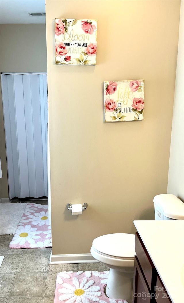 bathroom with toilet, vanity, visible vents, baseboards, and tile patterned floors