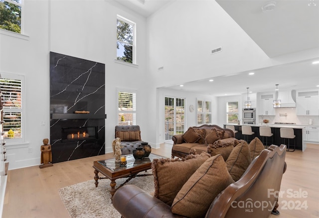 living room featuring light hardwood / wood-style flooring, plenty of natural light, and a high ceiling