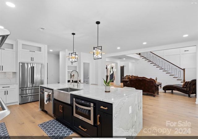 kitchen with sink, appliances with stainless steel finishes, pendant lighting, and white cabinetry