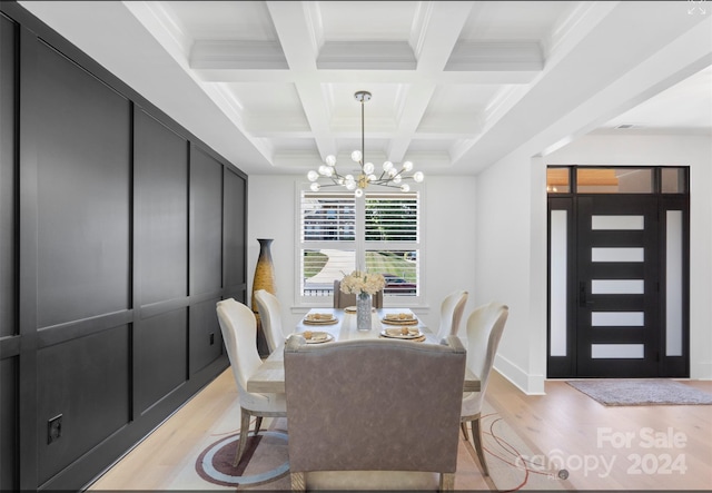 dining space with beam ceiling, an inviting chandelier, ornamental molding, light hardwood / wood-style floors, and coffered ceiling