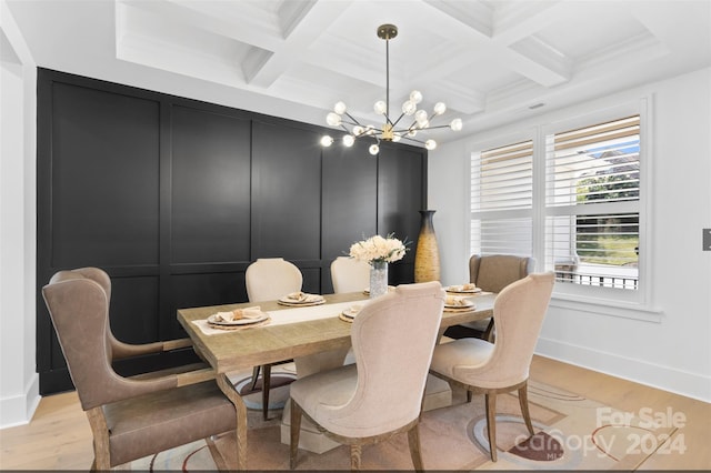 dining room featuring beam ceiling, a chandelier, light wood-type flooring, ornamental molding, and coffered ceiling