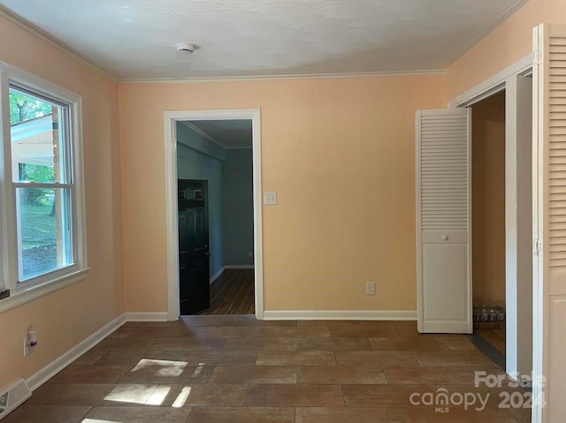 unfurnished bedroom with a spacious closet, a closet, and ornamental molding