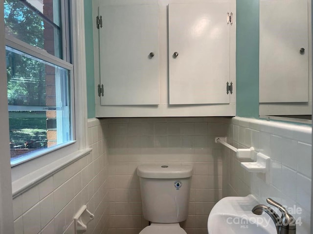 bathroom featuring toilet and tile walls