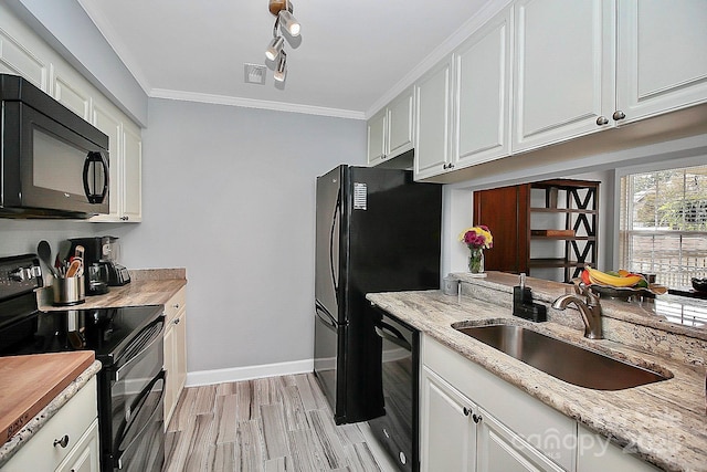 kitchen with light stone countertops, sink, crown molding, white cabinets, and black appliances