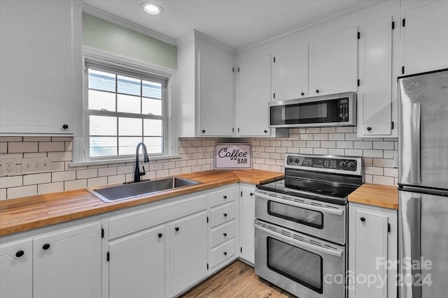 kitchen featuring butcher block countertops, sink, white cabinetry, and stainless steel appliances