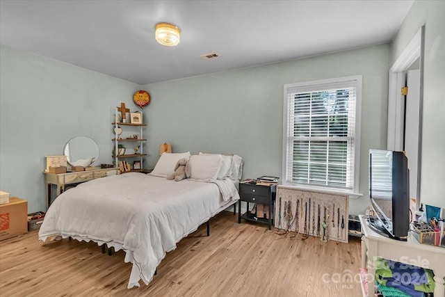 bedroom with radiator and light wood-type flooring