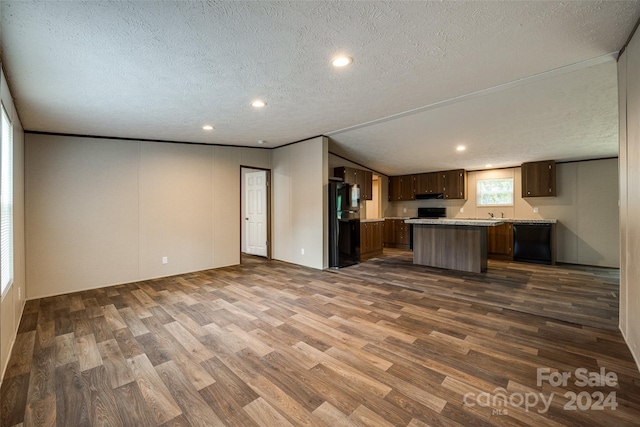 kitchen with a textured ceiling, a center island, lofted ceiling, black appliances, and dark hardwood / wood-style flooring