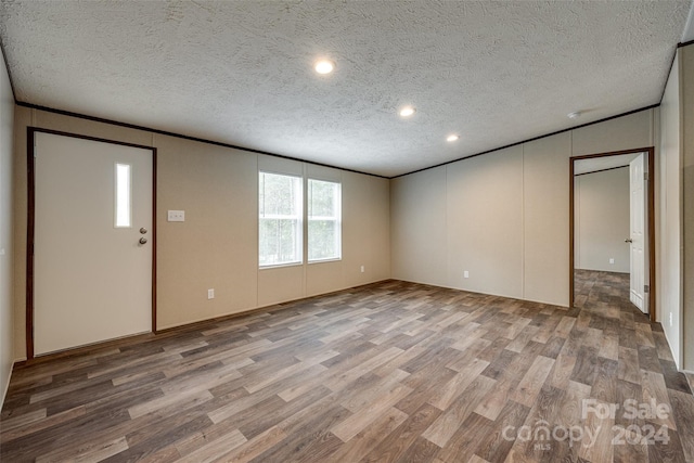 interior space featuring hardwood / wood-style flooring, a textured ceiling, and ornamental molding