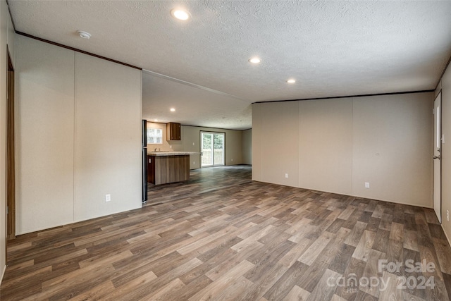 unfurnished living room with hardwood / wood-style flooring and a textured ceiling