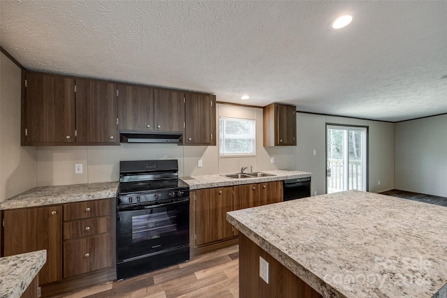 kitchen with black appliances, light wood-type flooring, sink, and a textured ceiling