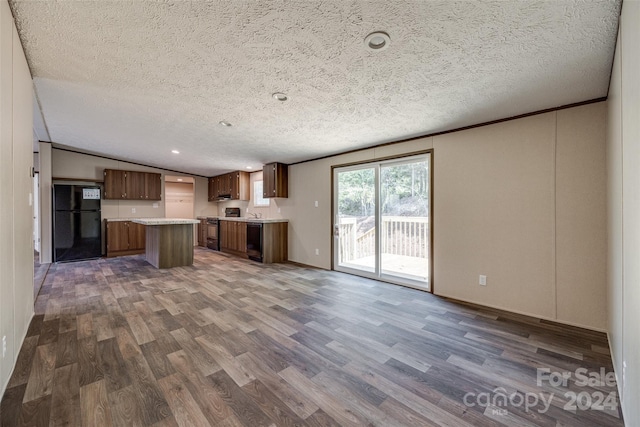 kitchen with dark hardwood / wood-style floors, black fridge, lofted ceiling, a textured ceiling, and a center island