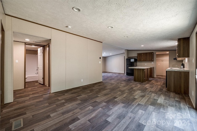 kitchen featuring dark wood-type flooring, a textured ceiling, black fridge, and sink