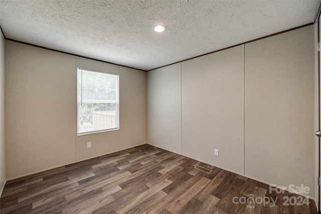 unfurnished room with dark hardwood / wood-style flooring and a textured ceiling