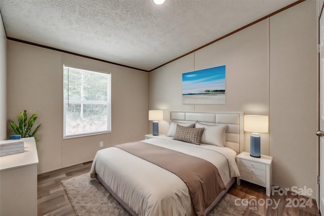 bedroom featuring wood-type flooring, vaulted ceiling, and a textured ceiling