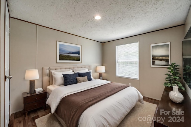 bedroom with dark wood-type flooring, a textured ceiling, and crown molding