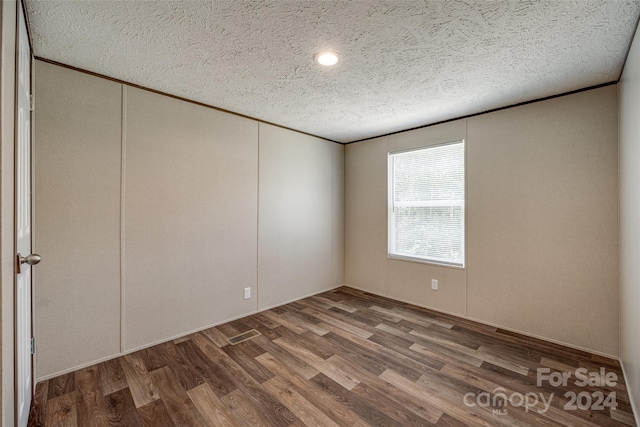 unfurnished room with a textured ceiling and hardwood / wood-style flooring