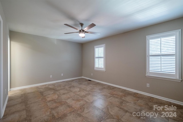 empty room featuring a wealth of natural light and ceiling fan