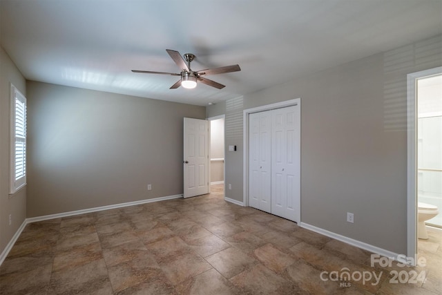 unfurnished bedroom with ceiling fan, ensuite bathroom, and a closet