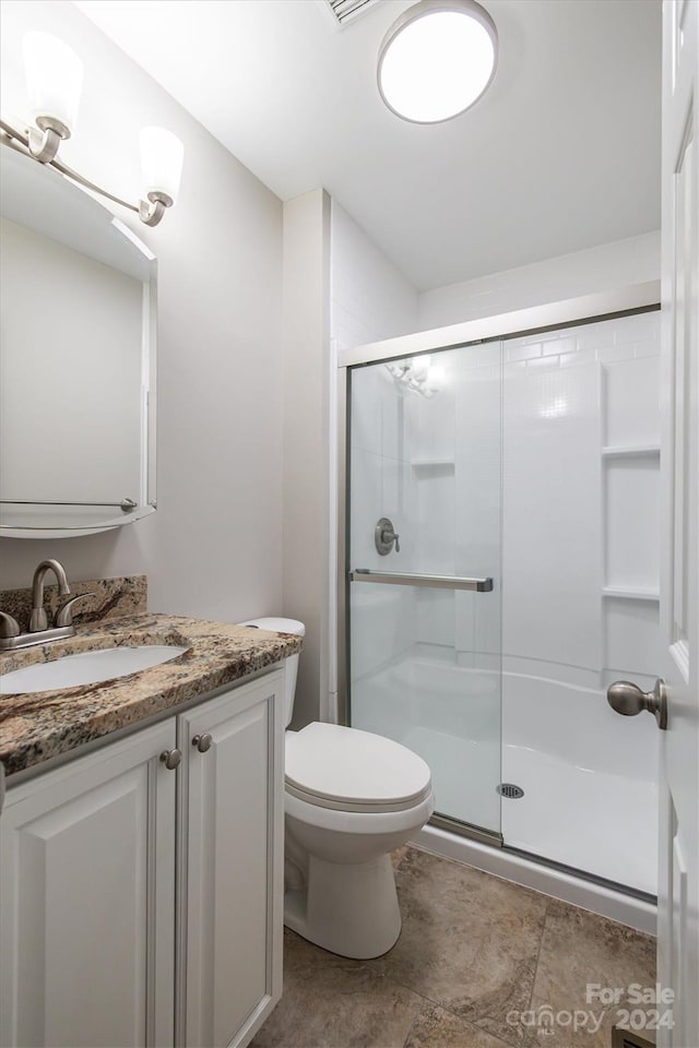 bathroom featuring vanity, toilet, and a shower with shower door