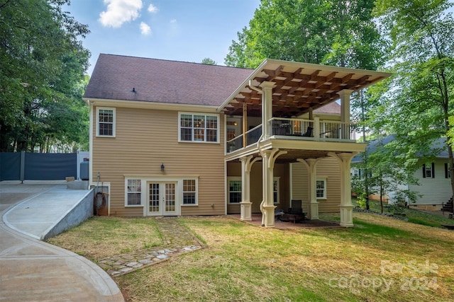 rear view of house with a patio area, a balcony, a yard, and french doors