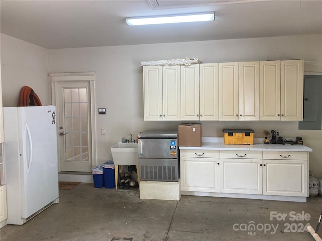 garage featuring white refrigerator, sink, and electric panel